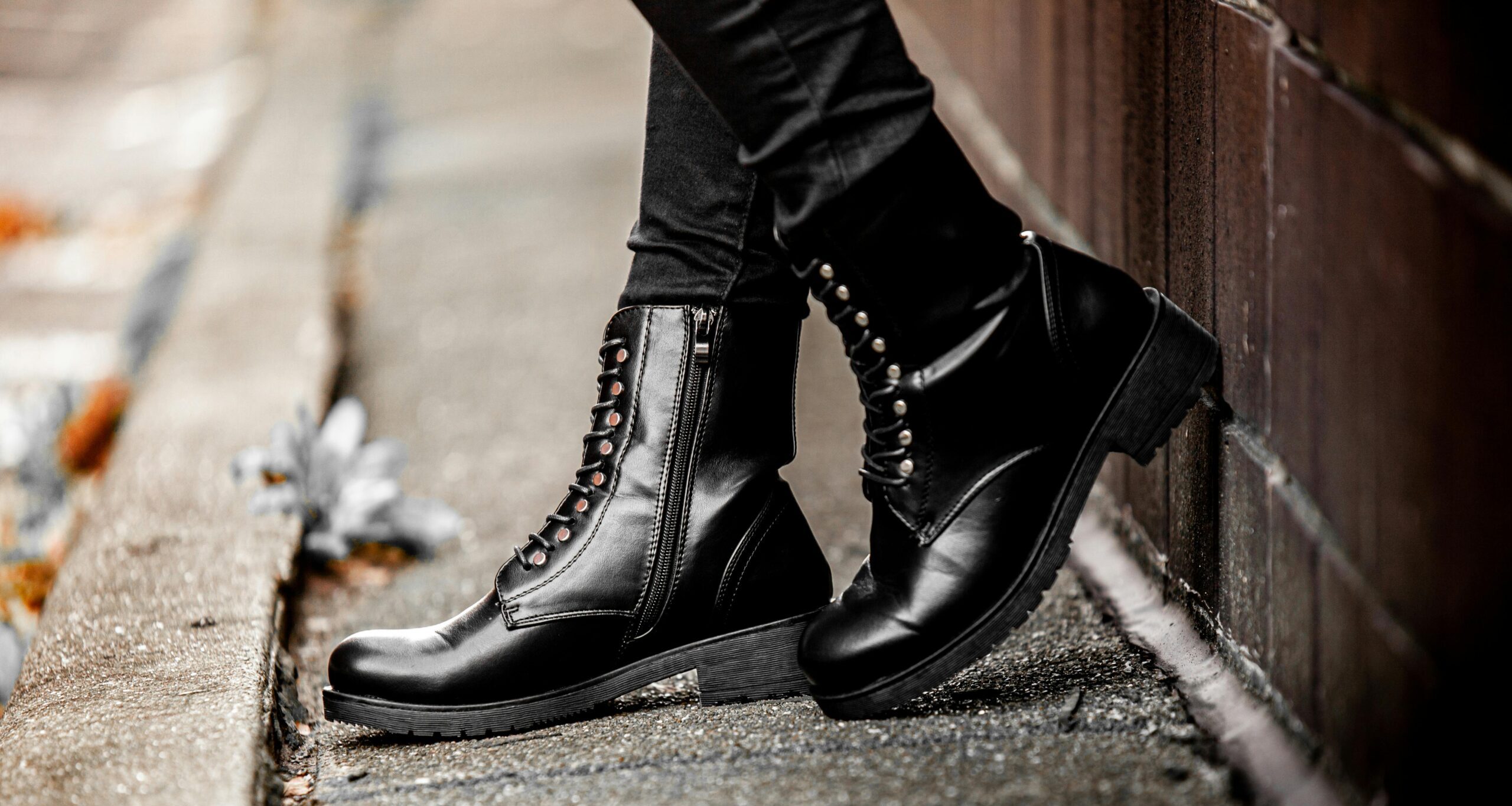 Black leather lace-up ankle boots with zipper detail on urban street